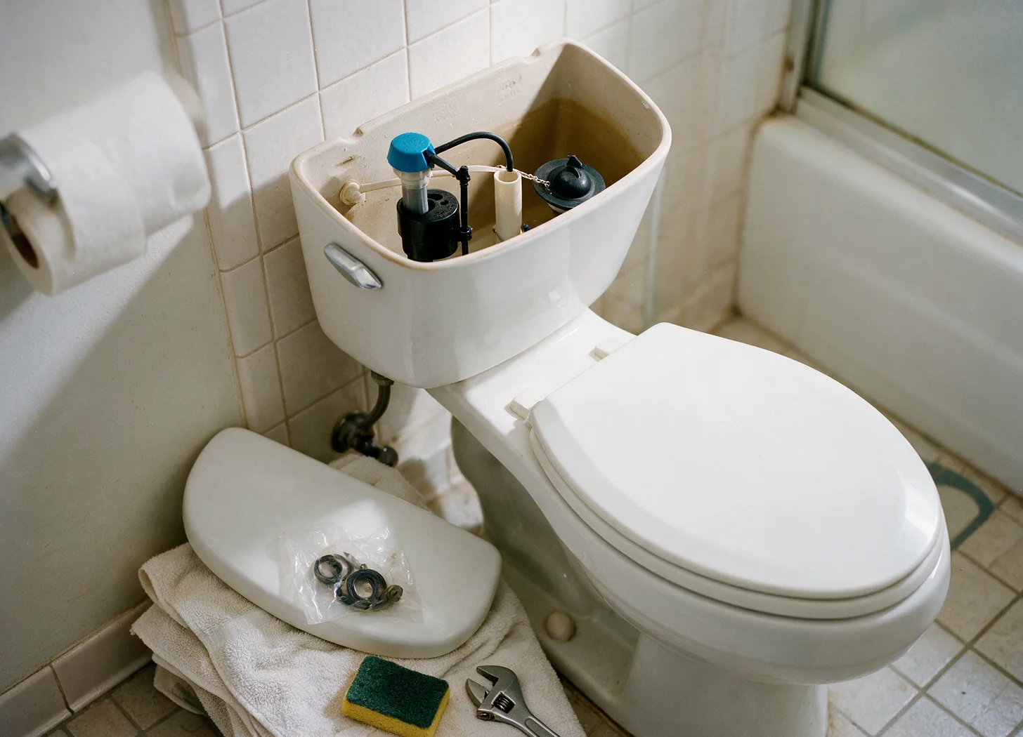An open toilet tank with a new fill valve and flapper installed